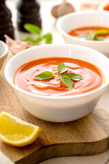Tomato soup with fresh basil in white bowls. Bright background. Vegan creamy soup.