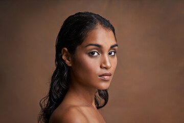 All natural girl. Studio shot of a beautiful young woman against a brown background.