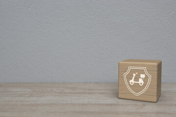 Motorcycle with shield flat icon on wood block cube on wooden table over white wall background, Business motorbike insurance concept