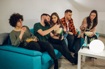 Friends watching movie at home and eating snacks