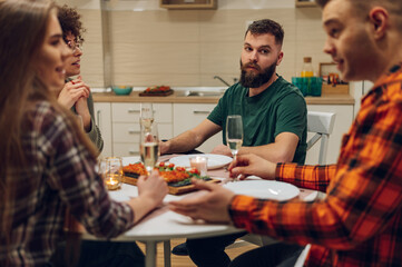 Group of friends enjoying dinner while sitting at the kitchen table together