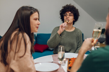 Group of friends enjoying dinner while sitting at the kitchen table together
