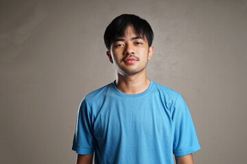 Handsome young man with middle parted bangs wearing blue t-shirt smiling at the camera