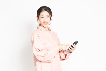 白背景の前でスマホを使っている女性