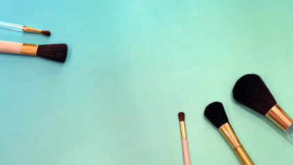 Flat lay of make-up brushes in different sizes. On a greenish background.