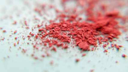 Closeup of a pile of red makeup powder crumbled into small pieces.