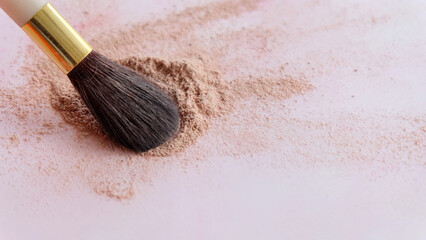 Closeup of a make-up brush, with the tip sweeping brown cosmetic foundation powder into a pile.