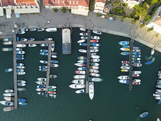 Aerial panoramic view of Balaklava landscape with boats and sea in marina bay on sunset time. Crimea Sevastopol tourist attraction. Drone top view shot of port for luxury yachts, boats and sailboats