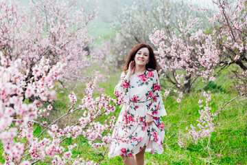 Fototapeta na wymiar a woman in the garden of flowering peach trees in the spring