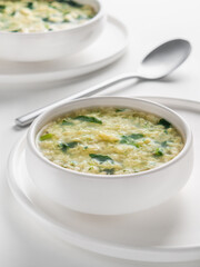Fresh homemade Italian soup Stracciatella alla Romana with spinach. Egg drop soup. Vertical. Selective focus. High key.