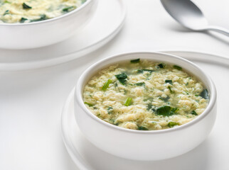 Traditional Italian soup Stracciatella alla Romana with spinach. Сlassic Italian egg drop soup. Horizontal. Selective focus. High key.