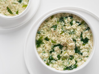 Portion of italian soup stracciatella in a white bowl on a white background