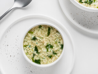 Homemade Italian soup Stracciatella with spinach. Egg drop soup in a white plates. Flat Lay. Horizontal. High key.