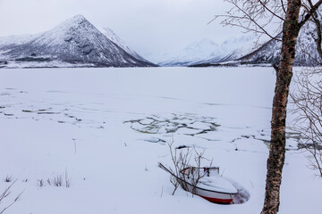 Boat in the ice on frozen lake at Blokken. Lofoten Islands Norway.