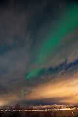 Aurora borealis through the clouds at Blokken in Lofoten Islands. Norway.