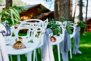 rose petals for the wedding lies on white chairs for the ceremony floristry