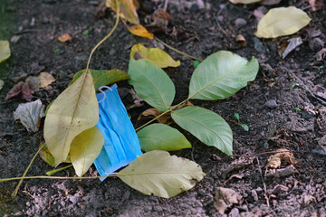 face mask lies in the trash on the ground dry leaves covid coronavirus end ecology