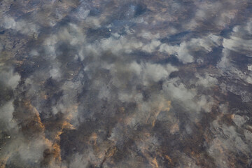 sky reflected in the water of the river dirty sand
