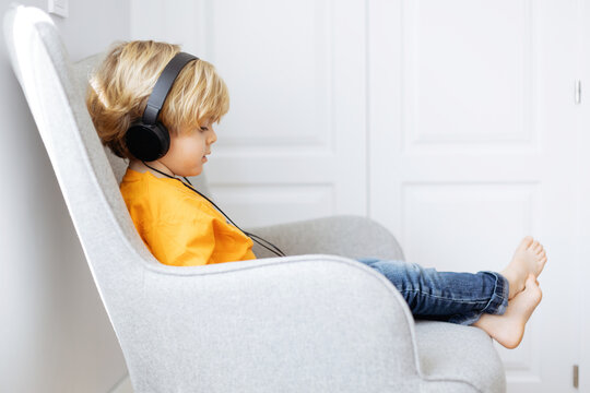 Barefoot boy in headphones watching cartoons on tablet
