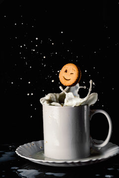 Cookie falling in splattering milk in mug
