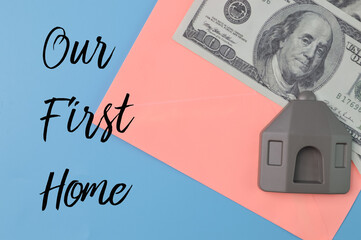 Money banknotes, toy house and envelope with text OUR FIRST HOME