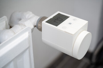 Modern smart heating valve with thermostat retrofitted to an old hot water heating system radiator to control room temperature