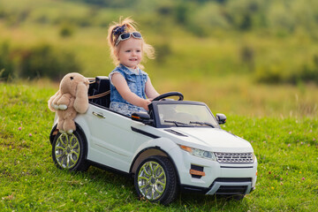 child rides in his car in nature