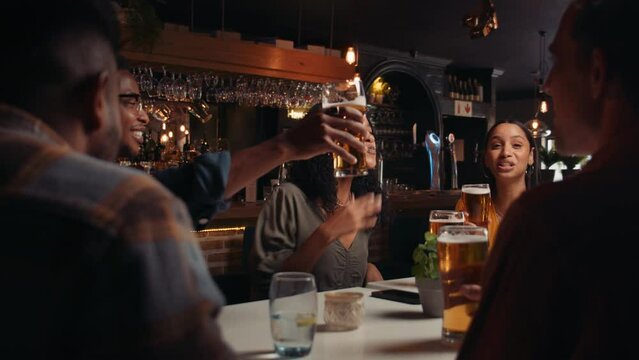 diverse group of friends making toast at dinner celebrating 