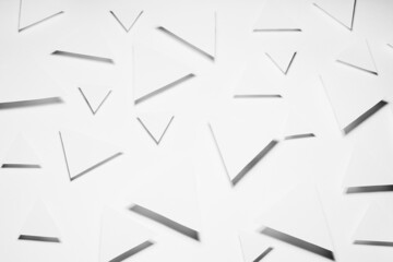 White triangles geometric pattern in hard light with strict grey shadows in random, top view. Minimalist modern abstract background.