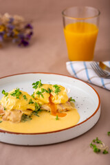 Eggs Benedict with a slice of bacon on toast and smothered in traditional hollandaise sauce. Delicious breakfast menu item. Classic English starter. Closeup. 