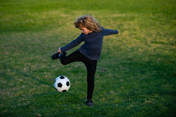 Soccer kid. Kids play football on summer stadium field. Little child boy kicking ball. Boy kicking football ball. Young boy with soccer ball doing flying kick.