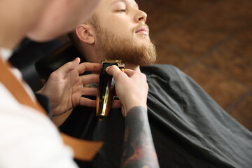 Professional hairdresser working with bearded client in barbershop, closeup