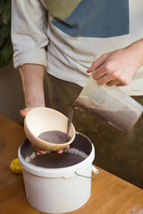 Potter Glazes Bowls in Workshop. Ceramic Artist Man glazing on master class. Pottery Making process, ceramic production