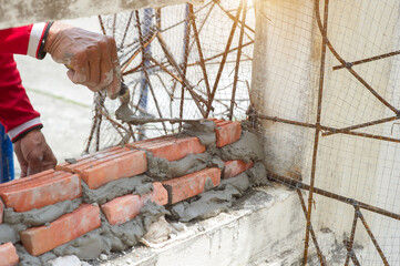 masonry worker make concrete wall by cement block and plaster at construction site