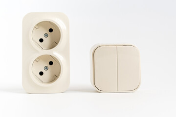 double socket and two-key light switch on white background. mechanical device for switching lighting circuit and two sockets connected by one monolithic case. shop of electronic devices for the home.