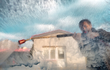 Man using water gun jet sprayer in car wash self-service