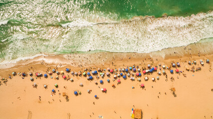 Aerial view top view drone of Beach showing colourful umbrellas and people relaxing on a summer day.