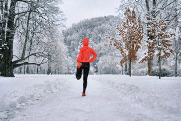 Running woman, girl runner on snow in park in winter sunny day.