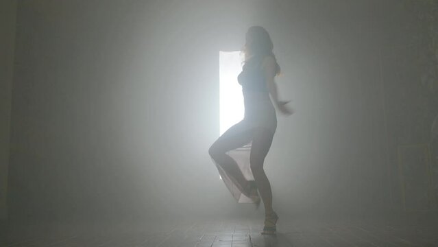 Woman dancing bachata dance indoors with smoke.