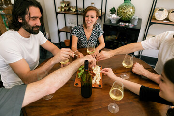friends sitting around the table with a glass of wine and a platter of salami and cheese