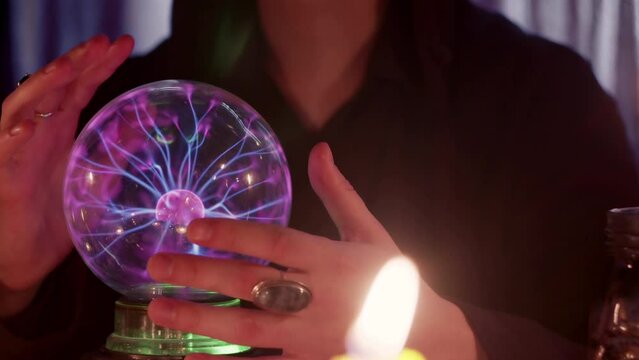 SIde view of male fortune teller casts a spells and performs ritual with crystal ball