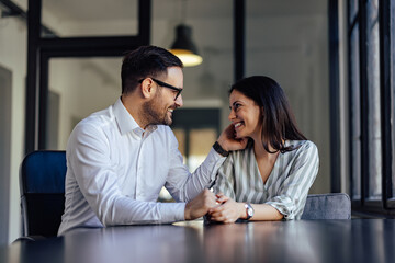 Business couple, sharing love at the office, smiling at each other.