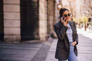 Fototapeta premium Positive young lady, holding hand in a pocket, talking to someon