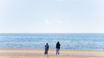 遠浅の海の浜辺に佇むカップル