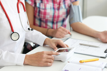 Female doctor using electronic stethoscope checking blood pressure to a patient in the hospital