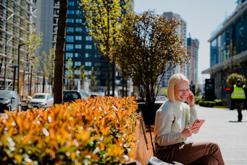 Happy young girl sitting in the park listening the music. Beautiful woman enjoy in sunny day