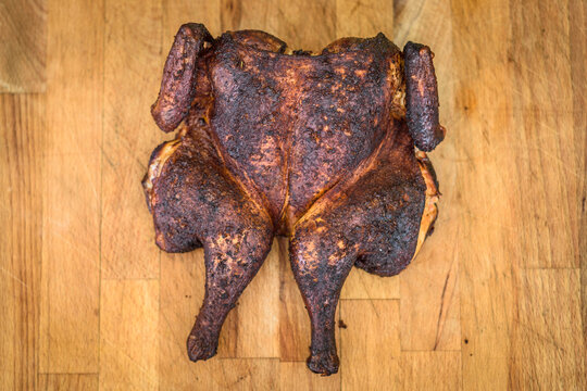 Traditional spatchcocked barbecue chicken al mattone on charcoal grill.