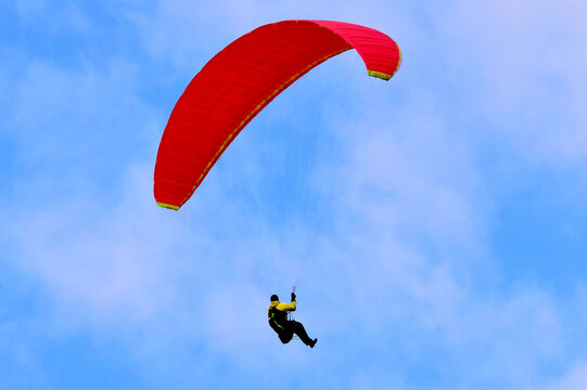 Paragleiter mit rotem Schirm im Flug