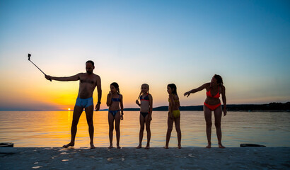 Family photographing selfie photo on a pier at sunset at the sea.