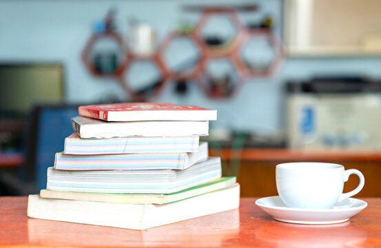 Stack of books and coffee cup in home interior.